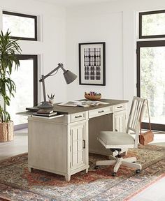 a desk with a chair, lamp and potted plant on it in front of two windows