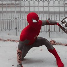 a man dressed as spider - man holding a tennis racquet in the snow