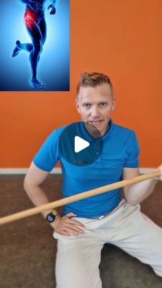 a man is holding a baseball bat and posing for a photo with an orange wall in the background