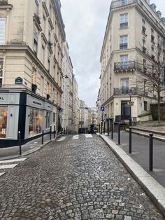 a cobblestone street in the middle of an old european city with tall buildings