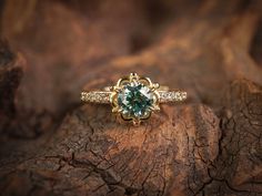 a green and white diamond ring sitting on top of a piece of wood