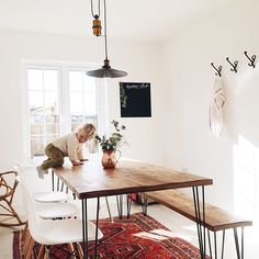 a woman sitting at a wooden table in a white room