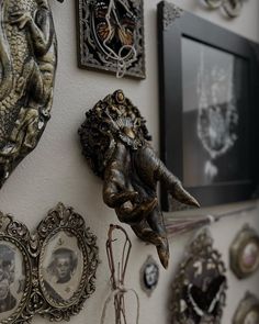 an elephant head is hanging on the wall next to several framed pictures and other decorative items