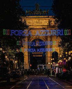 an illuminated arch in the middle of a city at night