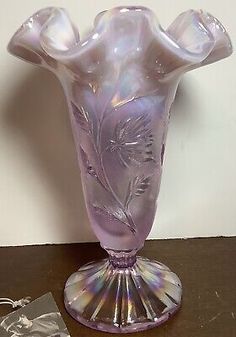 a purple glass vase sitting on top of a table next to a piece of silver foil