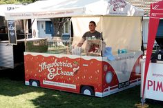 a man standing in front of a food truck selling strawberries and ice creams