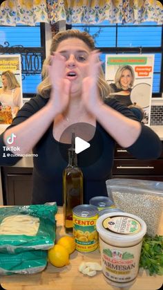 a woman standing in front of a table with food on it and hands up to her face