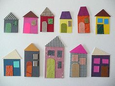 a group of paper houses sitting on top of a white wall