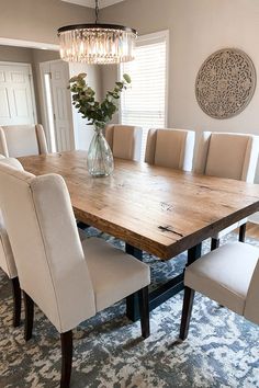 a dining room table with white chairs and a chandelier