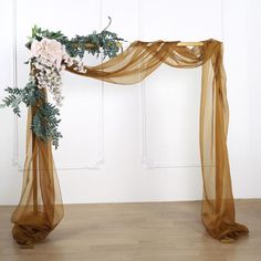 a wedding arch with flowers and greenery on the top is set up in front of a white wall