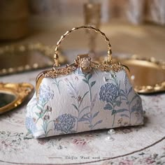 Add an original look to your outfit. These stunning purses are crafted with a focus on quality and detail. They’re especially suitable for weddings and special occasions. DESIGN – The fabrics are embossed with a floral design in pastel colours (Two styles). Enhanced with a gorgeous ornate clasp. FEATURES – Handle and chain shoulder strap. Size: 22 x 16 x 5 cm. MATERIAL – Polyester fabric, nylon liner. Fancy Purses, Coquette Kawaii, Kawaii Bag, Fairycore Coquette, Fairytale Fashion, Floral Interior, Fancy Bags, Vintage Purses, Pretty Bags