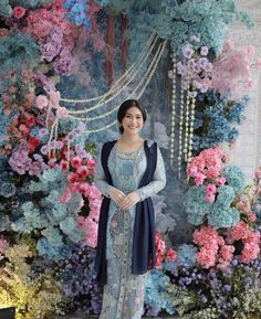 a woman standing in front of a floral backdrop