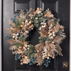 a christmas wreath on the front door with gold and silver ornaments hanging from it's sides