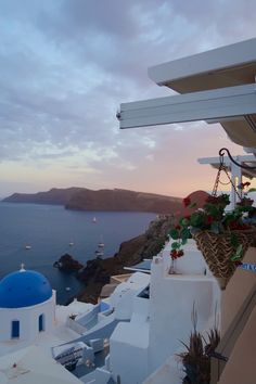 the sun is setting over the ocean and some white buildings with blue domes on them