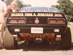 a man and woman standing next to a car with the words meander than a junkyard dog on it