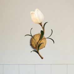 a wall mounted light with two white flowers on it