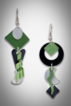 two pairs of earrings with green and black designs on them, hanging from metal hooks