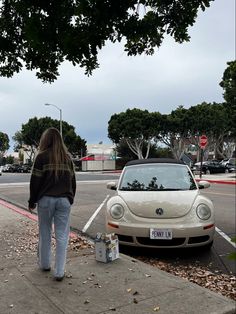 a woman walking down the sidewalk next to a parked car and an empty parking meter