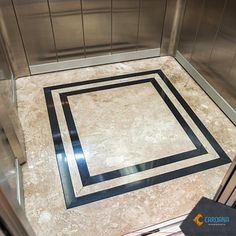 an elevator with marble flooring and black border around the area in front of it