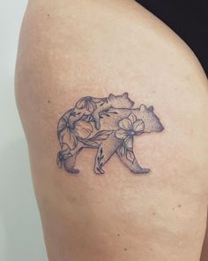 a woman's thigh with a tattoo of a bear and flowers on the side