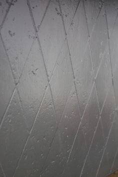 a white toilet sitting next to a wall covered in raindrops on it's side