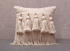 a white pillow with tassels on the front and back of it sitting on a table