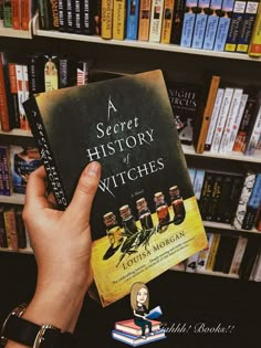 a person holding up a book in front of a bookshelf