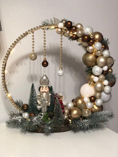 a christmas wreath with ornaments hanging from it's sides and an elf figurine in the middle