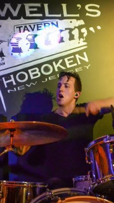 a man playing drums in front of a sign