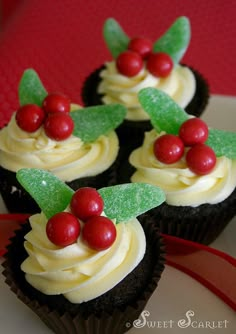 some cupcakes with white frosting and red berries on top are sitting on a plate