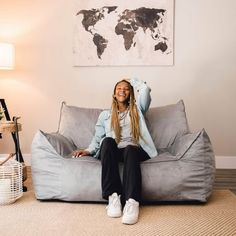 a woman sitting on top of a bean bag chair in front of a wall with a world map