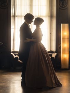 a man and woman standing in front of a window with sunlight streaming through the windows