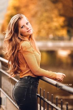 a beautiful young woman leaning on a fence