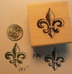 a wooden stamp with two fleur de lis on it next to a penny