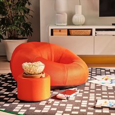 an orange chair with a bowl of popcorn on it sitting on a black and white checkered rug