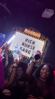 a group of people holding up signs in front of a crowd at a nightclub with neon lights