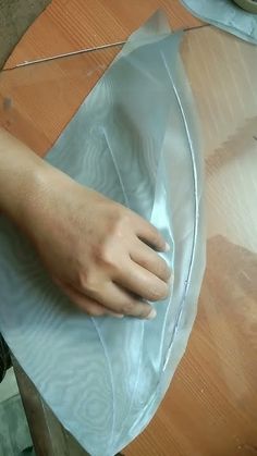 a person's hand is wrapped in plastic on top of a wooden table with scissors