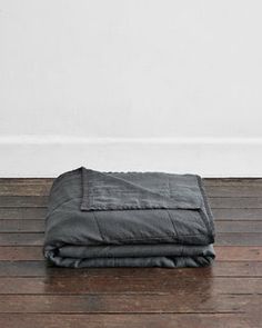 a black blanket sitting on top of a wooden floor in front of a white wall