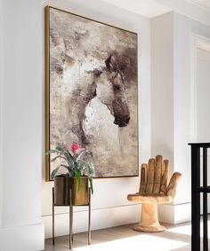 a painting hanging on the wall in a living room next to a chair and table