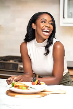 a woman sitting at a kitchen table with a plate of food in front of her