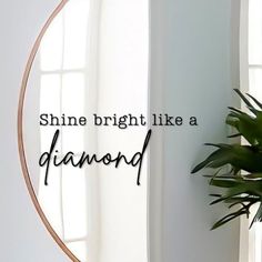 a round mirror with the words shine bright like a diamond on it next to a potted plant