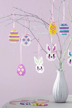 a white vase filled with easter decorations on top of a table next to a tree