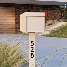 a mailbox in front of a house with numbers on it and grass next to it