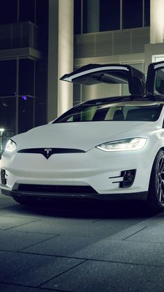 a white tesla car parked in front of a building