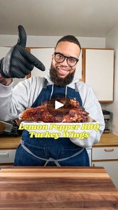 a man in an apron holding up a piece of meat with the words lemon pepper bbq turkey wings on it