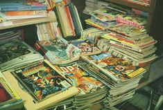 a pile of comic books sitting on top of a table next to a book shelf