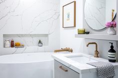 a white bath tub sitting next to a sink under a round mirror in a bathroom