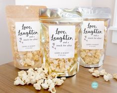 three bags of love laughter popcorn sitting on top of a wooden table next to each other