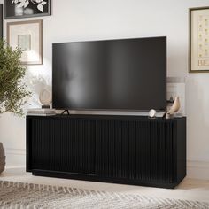 a flat screen tv sitting on top of a wooden entertainment center next to a potted plant