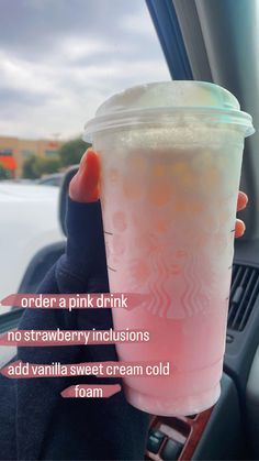 a person holding up a pink drink in their hand with information about it on the cup